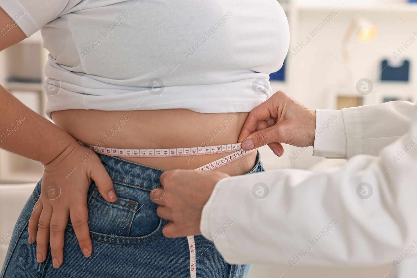 Photo of Weight loss. Nutritionist measuring patient's waist with tape in clinic, closeup