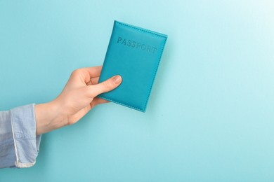 Photo of Woman holding passport in cover on turquoise background, closeup. Space for text