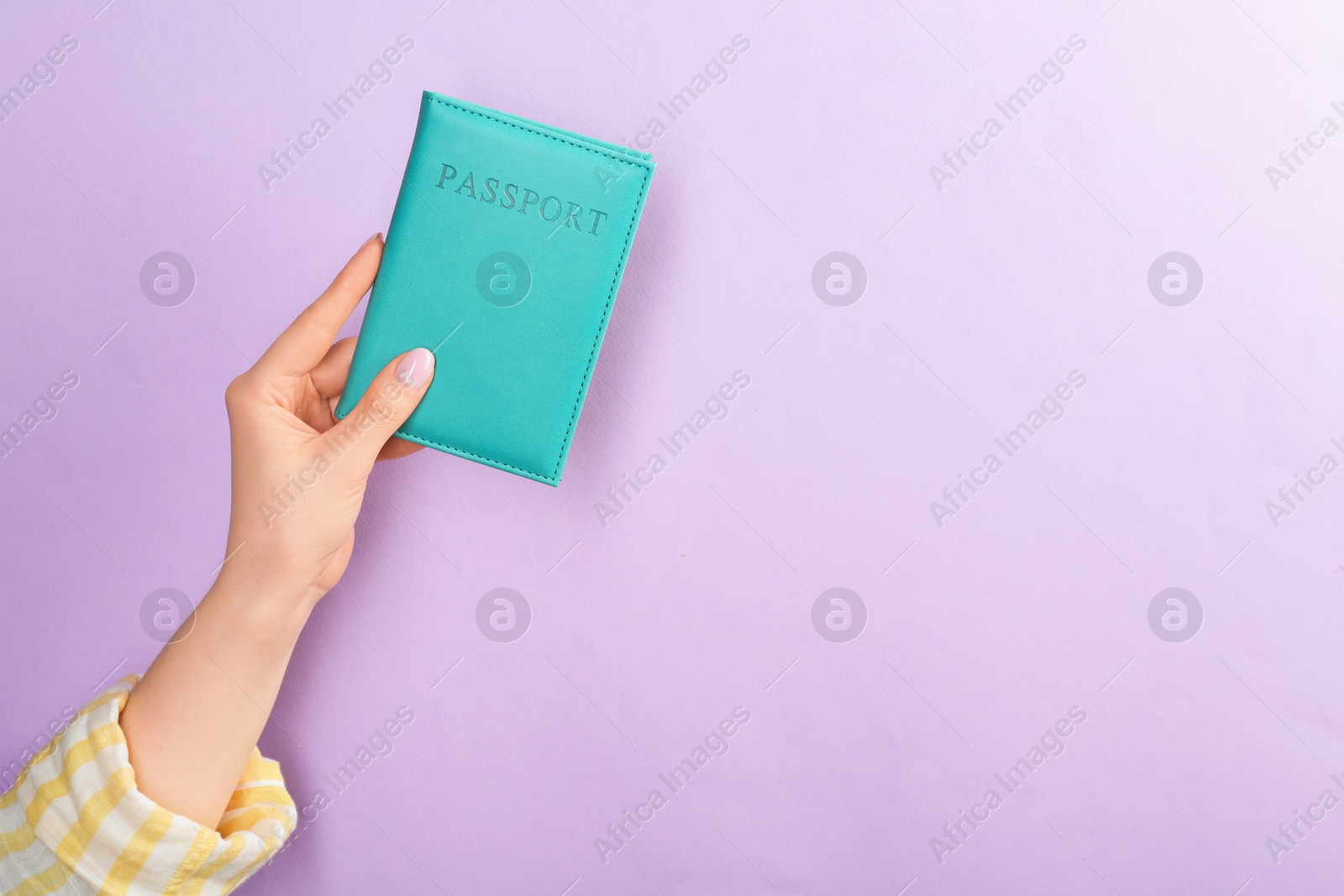 Photo of Woman holding passport in turquoise cover on violet background, closeup. Space for text