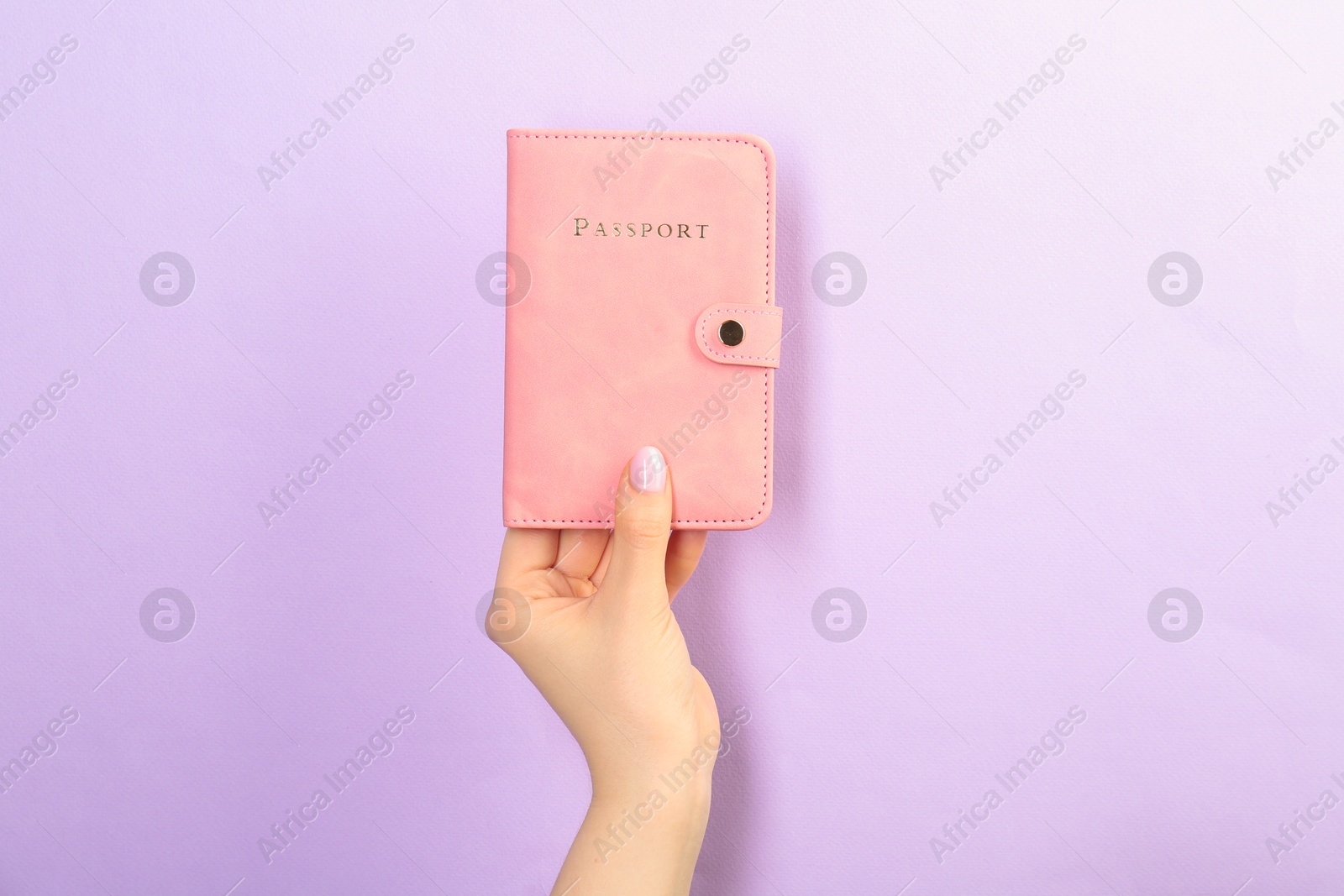 Photo of Woman holding passport in pink cover on violet background, closeup