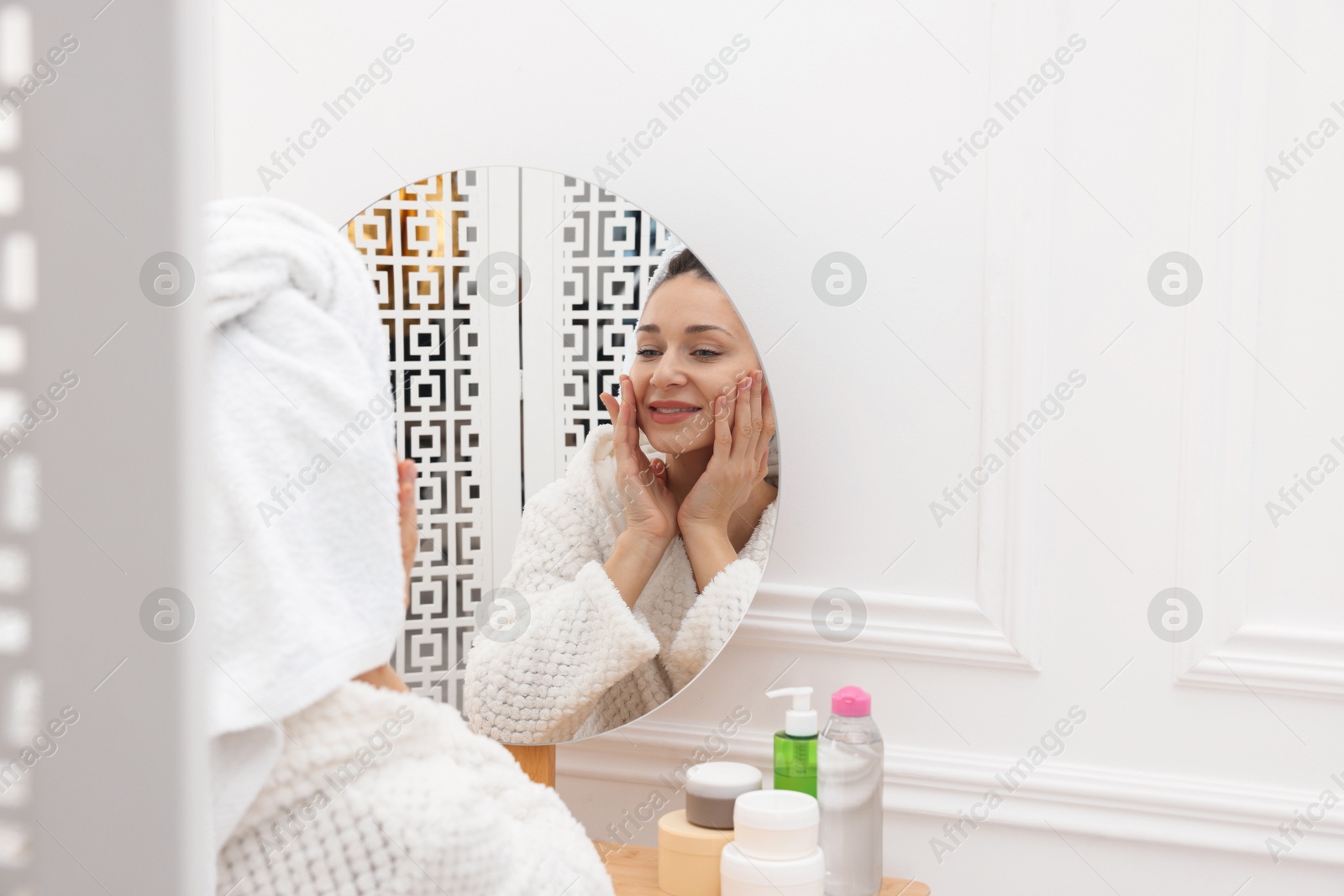 Photo of Spa day. Beautiful woman with towel on head near mirror indoors, space for text