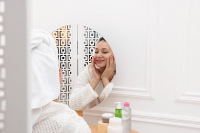 Photo of Spa day. Beautiful woman with towel on head near mirror indoors, space for text