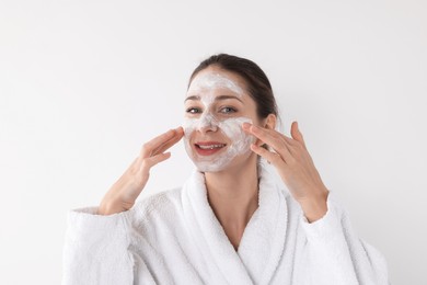 Photo of Spa day. Beautiful woman applying mask onto her face on white background