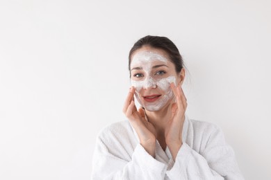 Photo of Spa day. Beautiful woman applying mask onto her face on white background, space for text