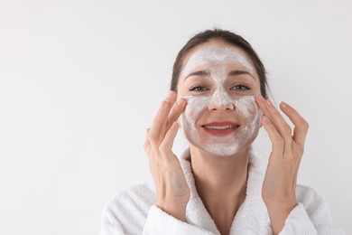 Photo of Spa day. Beautiful woman applying mask onto her face on white background, space for text