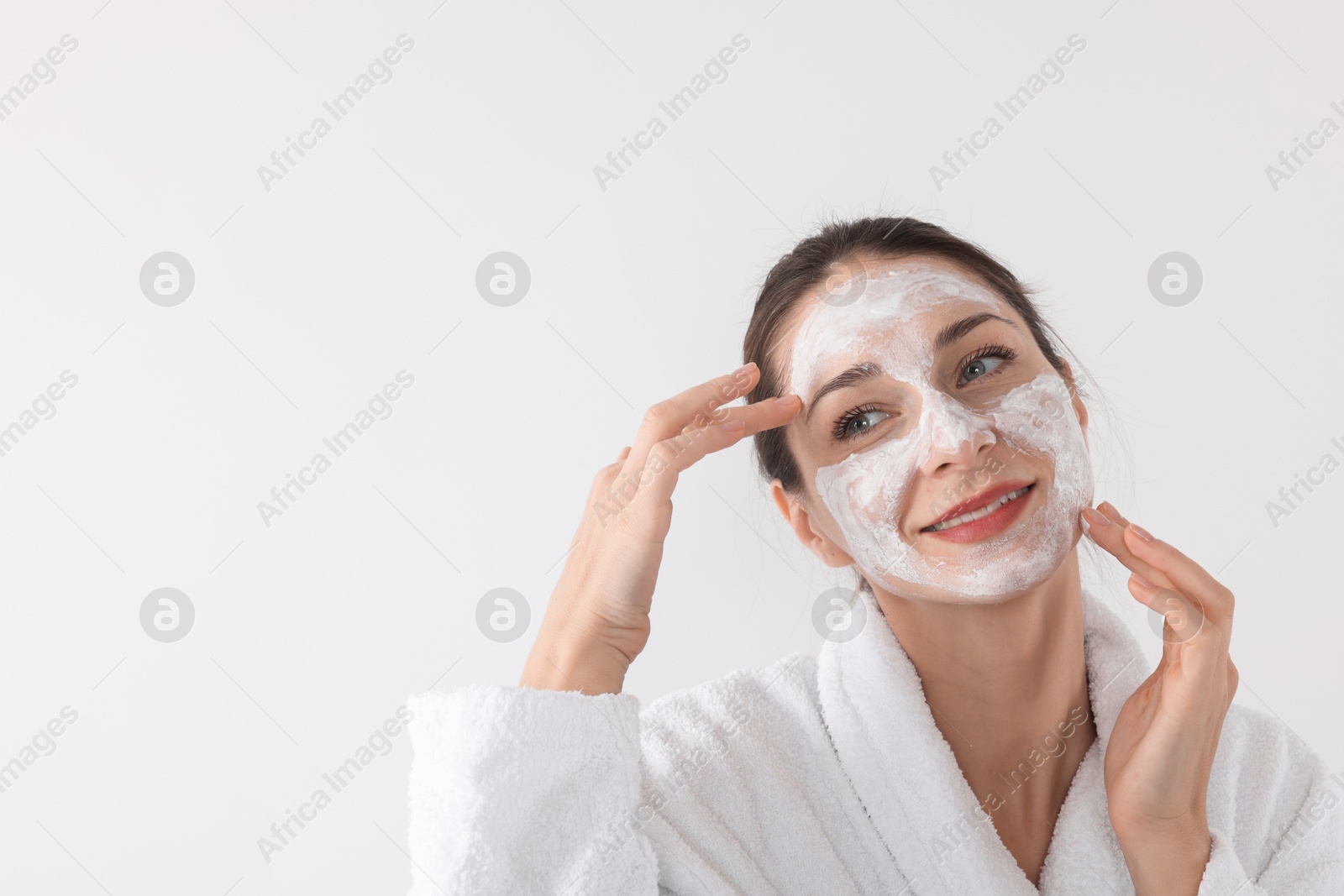 Photo of Spa day. Beautiful woman applying mask onto her face on white background, space for text