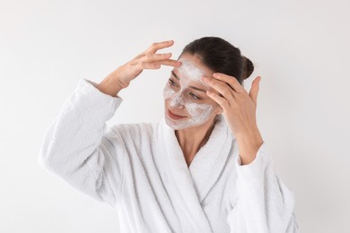 Photo of Spa day. Beautiful woman applying mask onto her face on white background