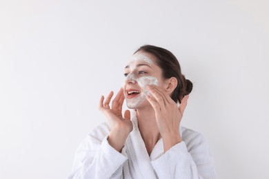 Photo of Spa day. Beautiful woman applying mask onto her face on white background