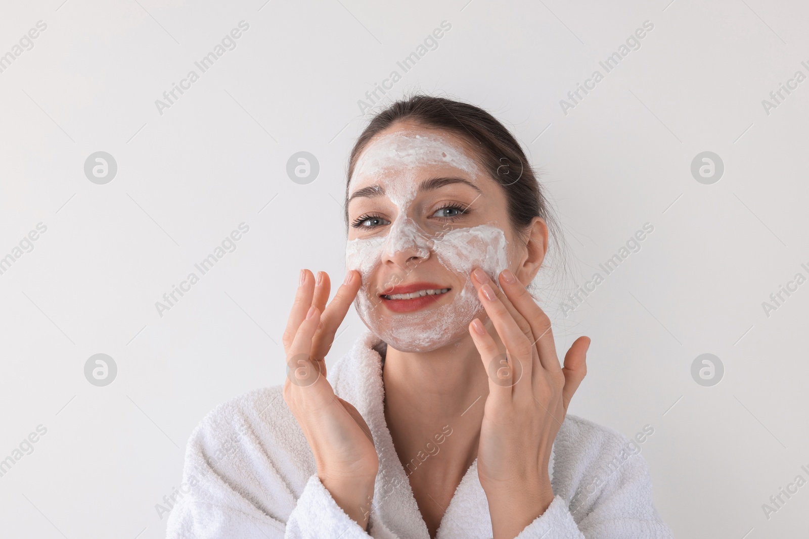 Photo of Spa day. Beautiful woman applying mask onto her face on white background