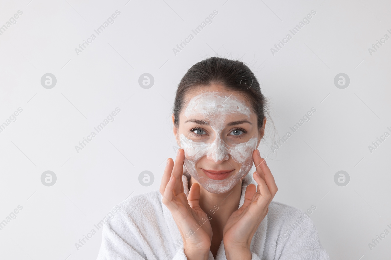 Photo of Spa day. Beautiful woman applying mask onto her face on white background