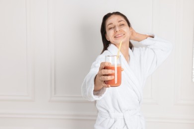 Photo of Spa day. Beautiful woman with face mask and glass of juice indoors, selective focus