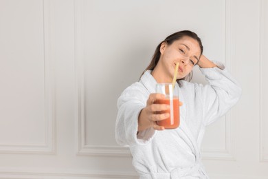 Photo of Spa day. Beautiful woman with face mask and glass of juice indoors, space for text