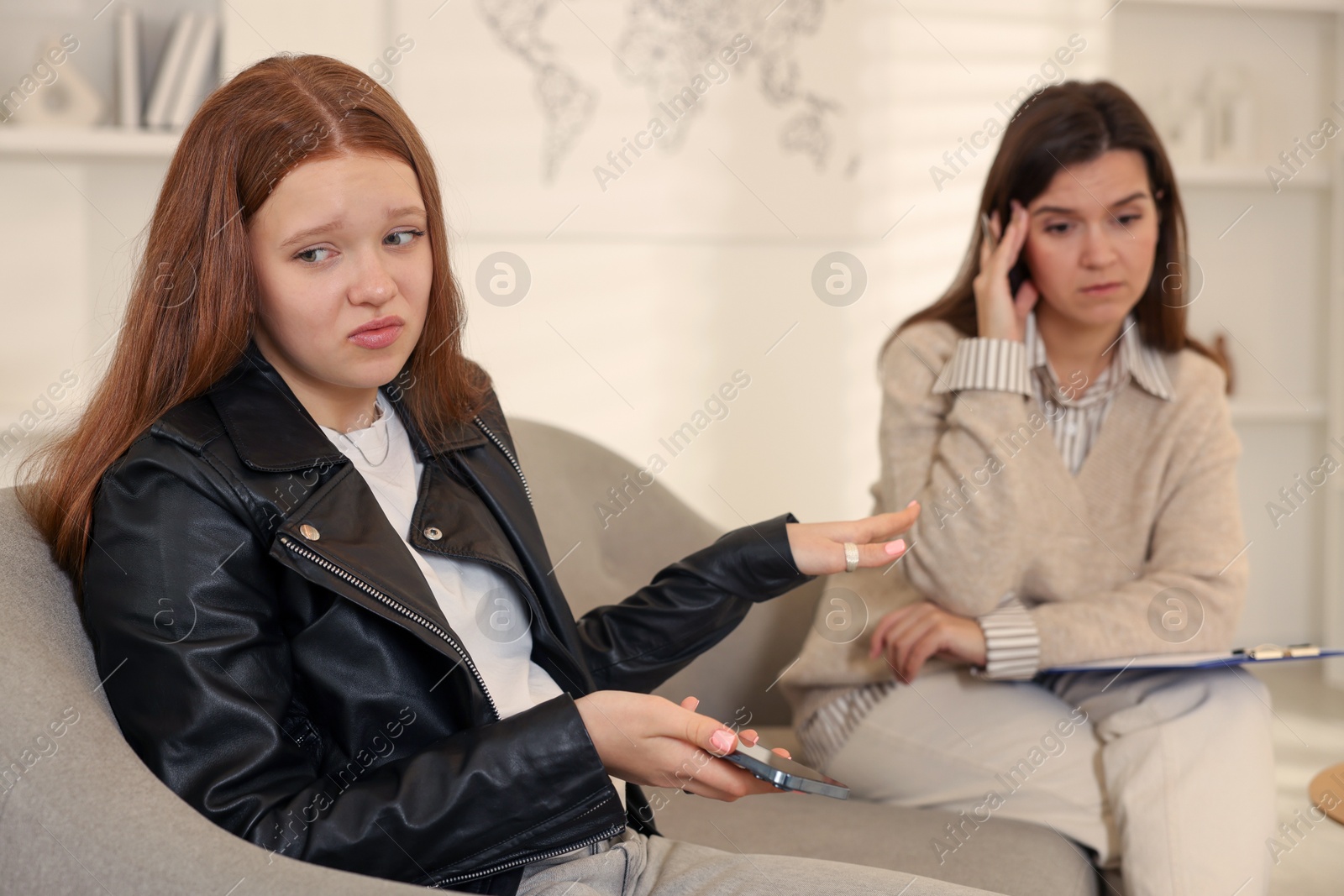 Photo of Psychologist working with difficult teenage girl in office, selective focus