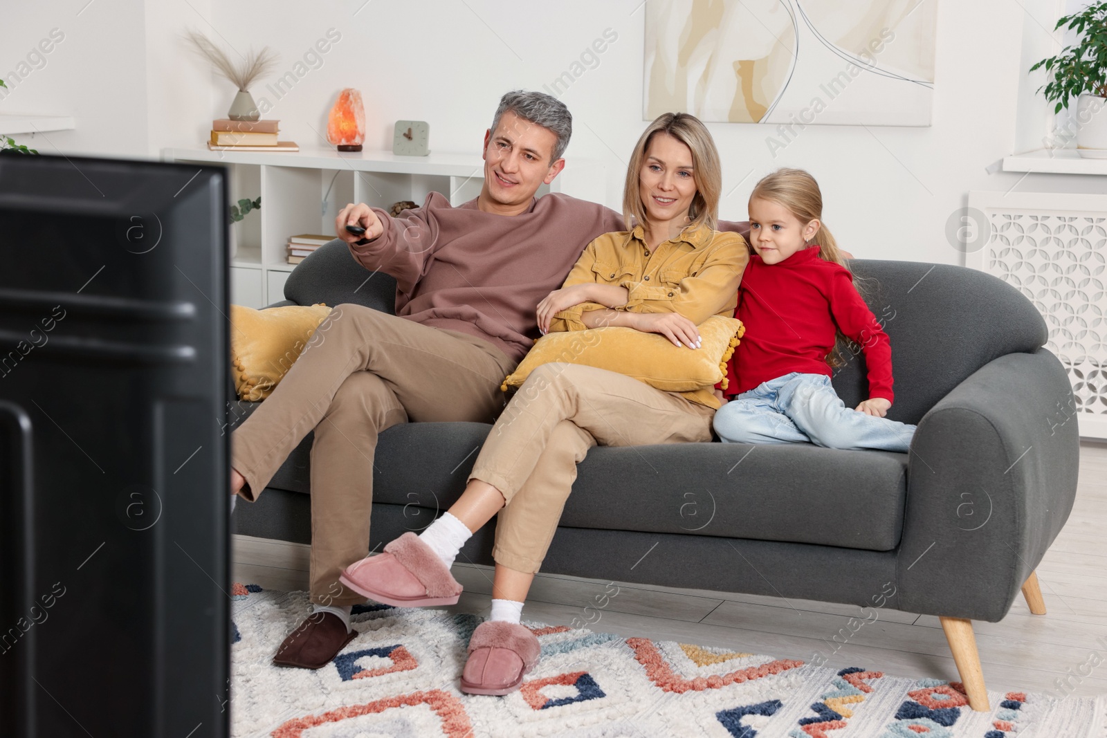 Photo of Family watching TV on sofa at home