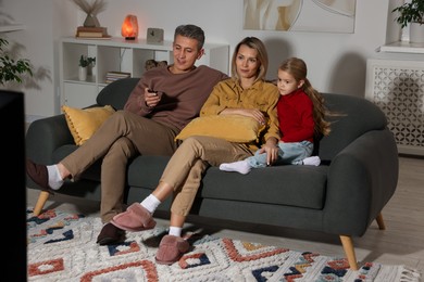 Photo of Family watching TV on sofa at home