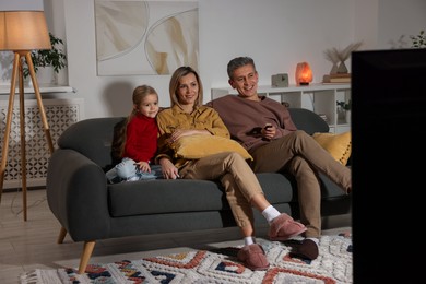 Photo of Family watching TV on sofa at home