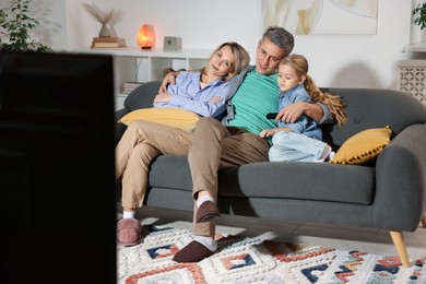 Photo of Family watching TV on sofa at home