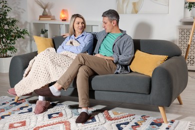 Photo of Lovely couple watching TV on sofa at home