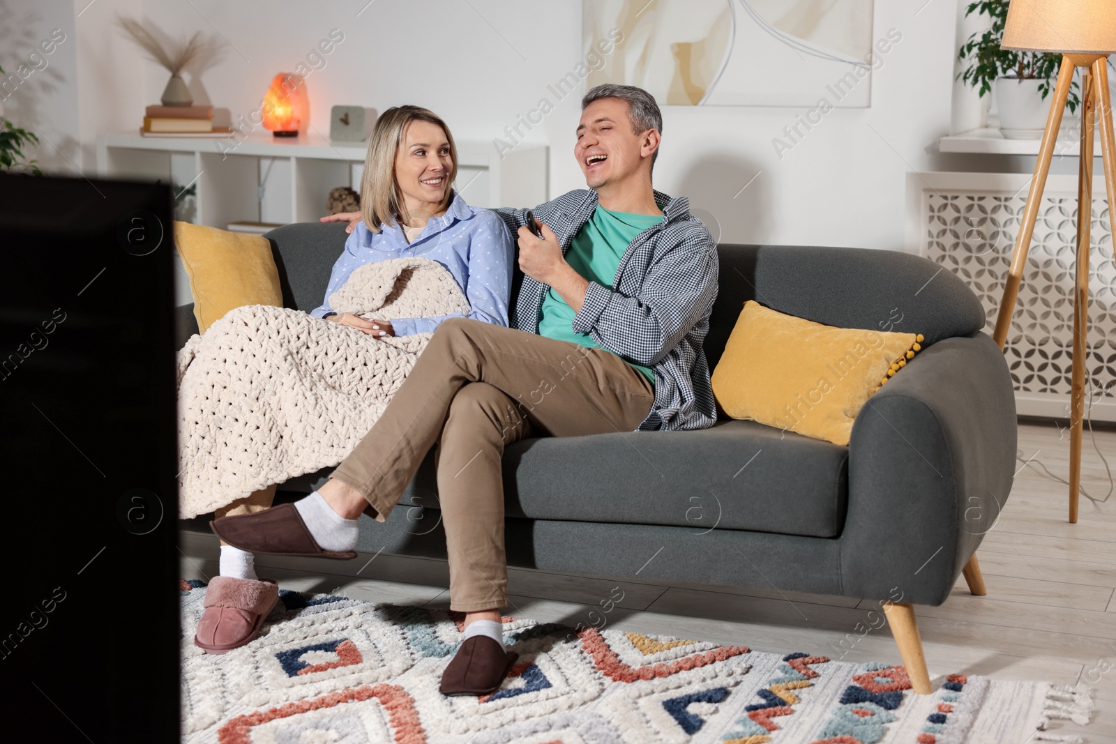 Photo of Lovely couple watching TV on sofa at home