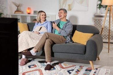 Photo of Lovely couple watching TV on sofa at home