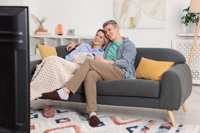 Photo of Lovely couple watching TV on sofa at home