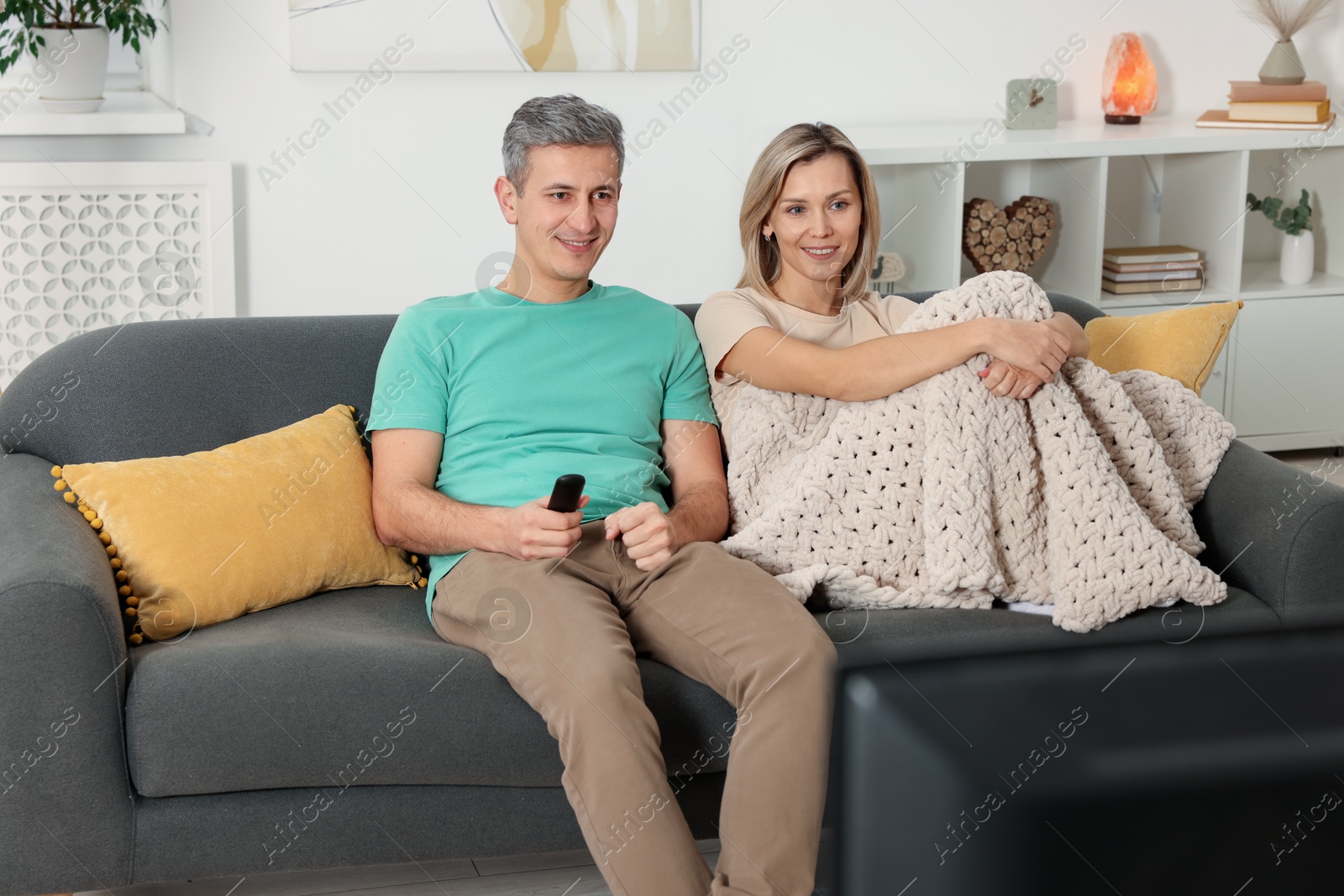 Photo of Lovely couple watching TV on sofa at home