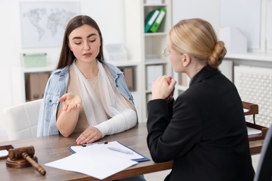 Photo of Injured woman having meeting with lawyer in office, selective focus