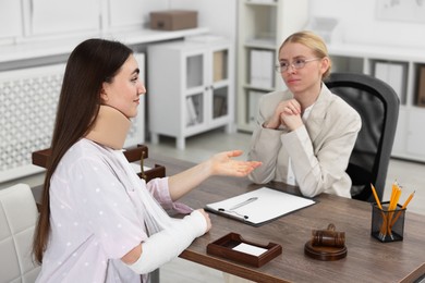 Photo of Injured woman having meeting with lawyer in office, selective focus