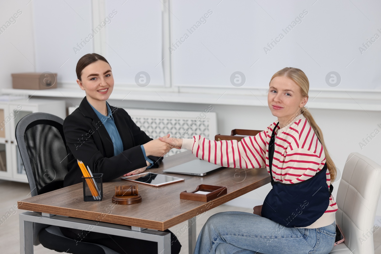 Photo of Injured woman and lawyer shaking hands in office