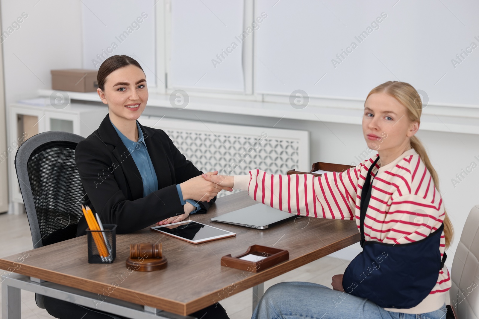 Photo of Injured woman and lawyer shaking hands in office