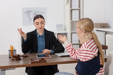 Photo of Injured woman having meeting with lawyer in office, selective focus