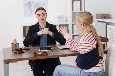 Photo of Injured woman having meeting with lawyer in office, selective focus