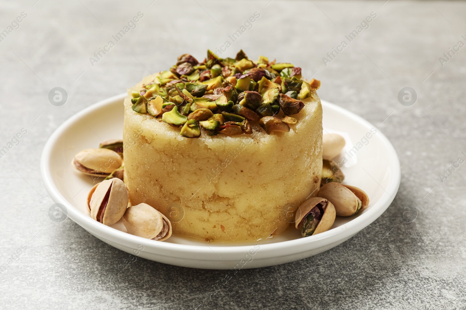 Photo of Delicious sweet semolina halva with pistachios on light grey table, closeup