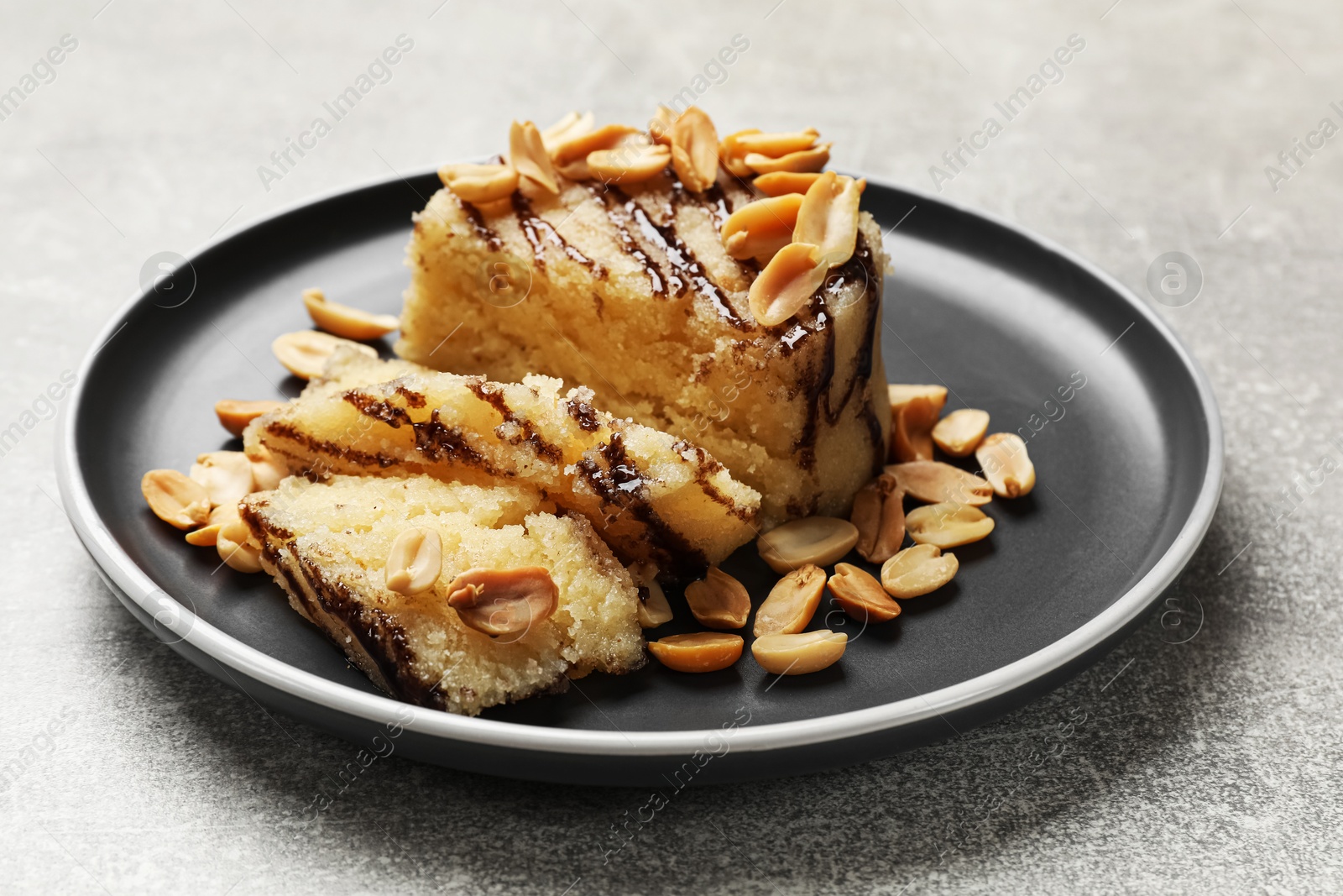 Photo of Delicious sweet semolina halva with peanuts on light grey table, closeup