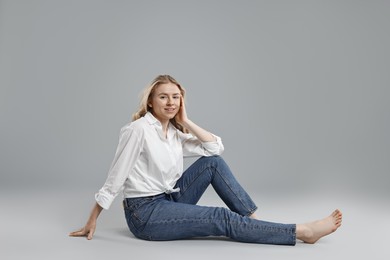 Photo of Smiling woman in stylish jeans on grey background