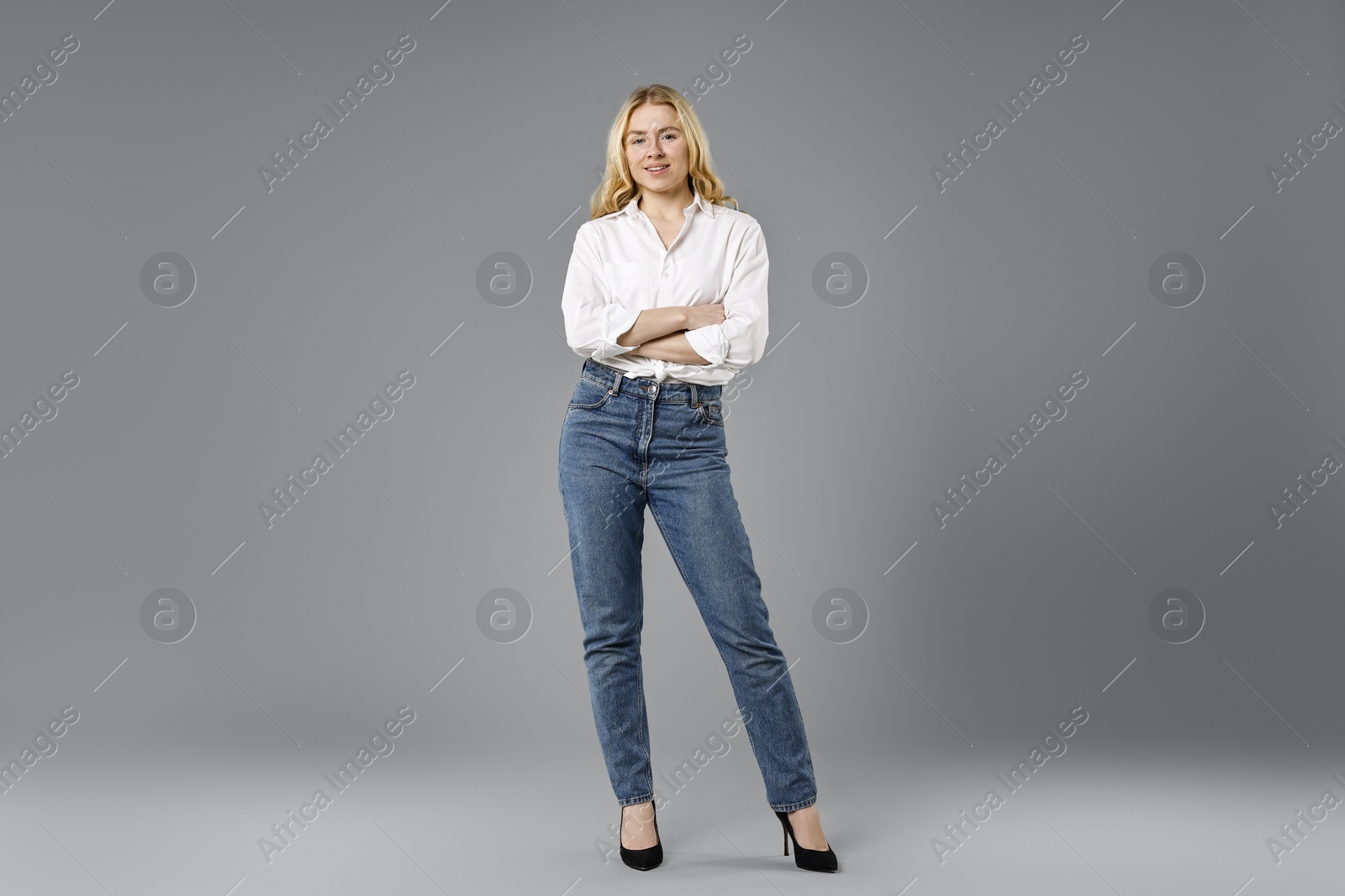 Photo of Smiling woman in stylish jeans on grey background