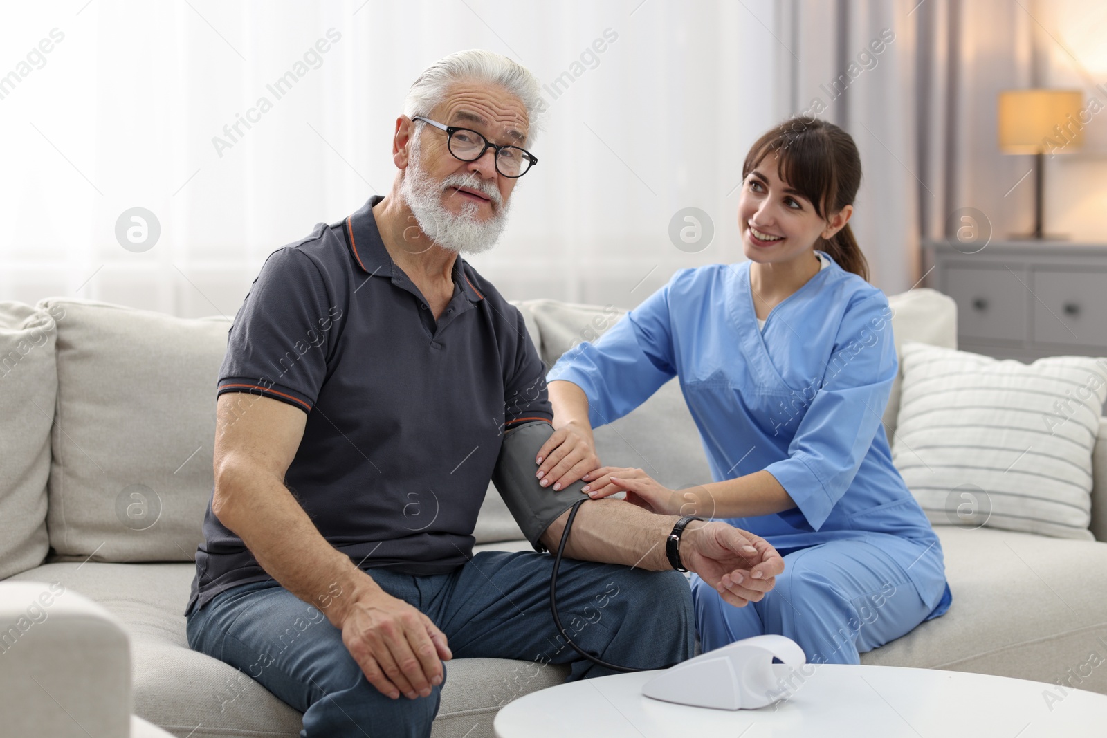 Photo of Nurse measuring senior man's blood pressure at home