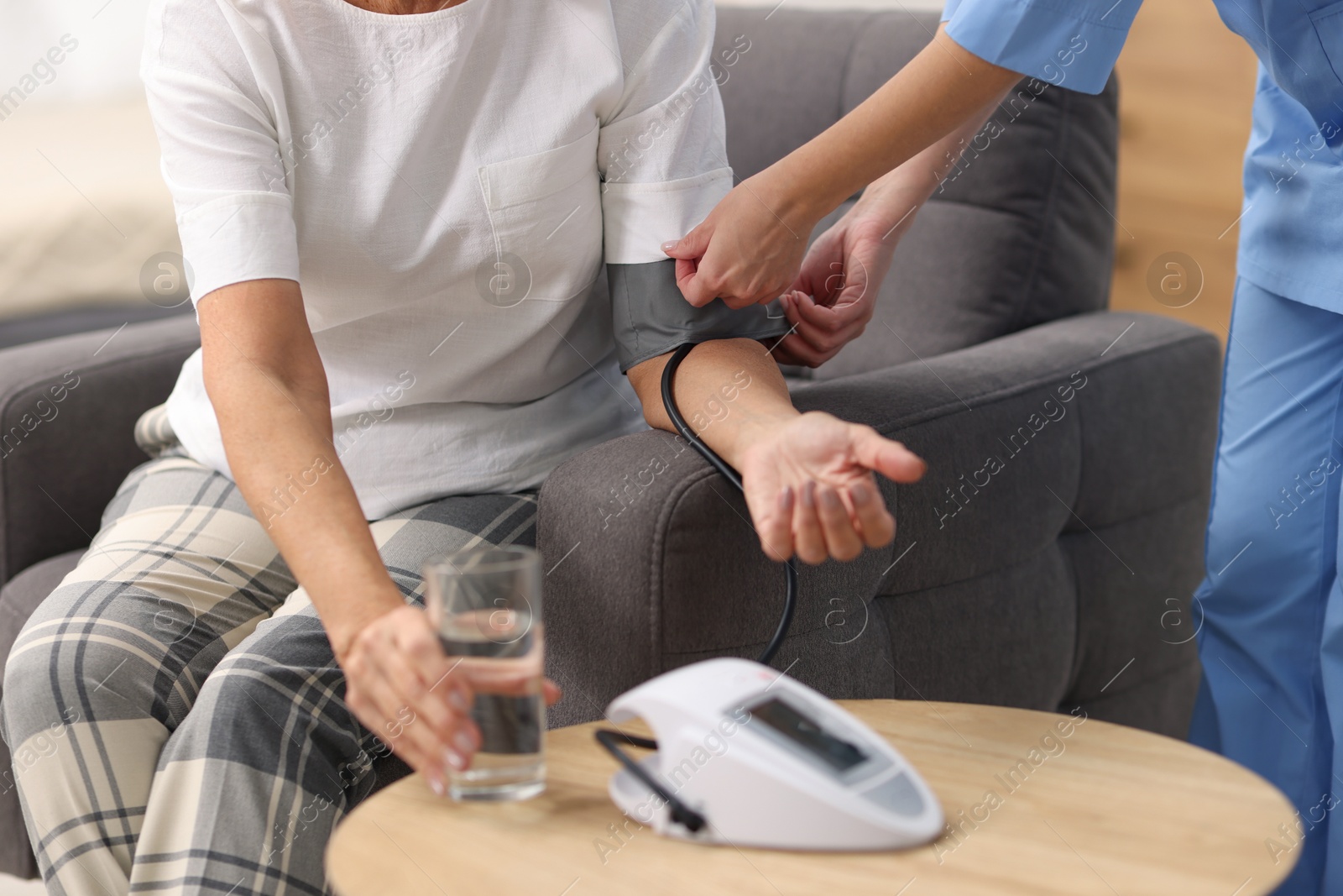 Photo of Nurse measuring senior woman's blood pressure at home, closeup