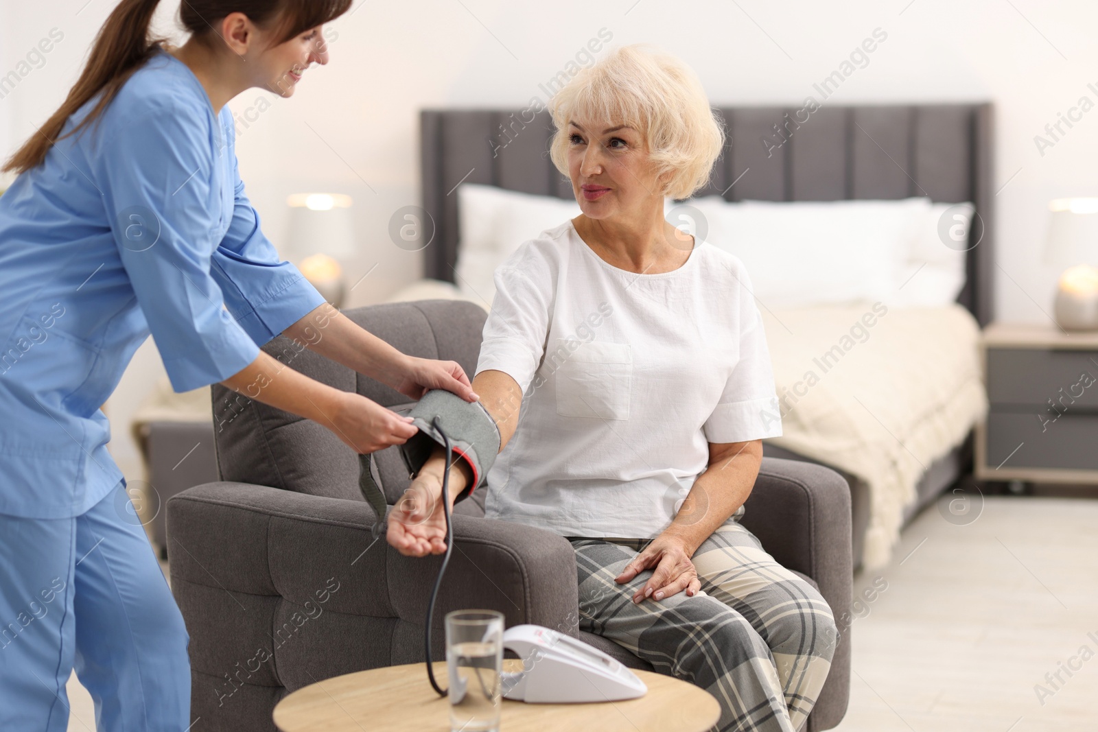 Photo of Nurse measuring senior woman's blood pressure at home