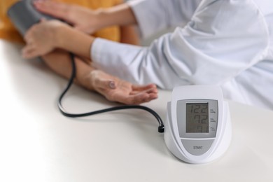 Photo of Doctor measuring senior woman's blood pressure at table, closeup