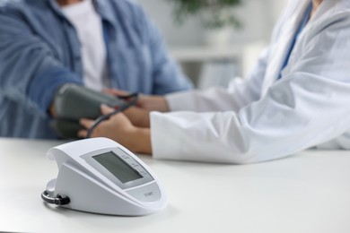 Photo of Doctor measuring senior man's blood pressure during appointment in hospital, closeup. Selective focus