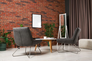 Photo of Soft armchairs, coffee table, mirror and houseplants in cozy living room. Interior design