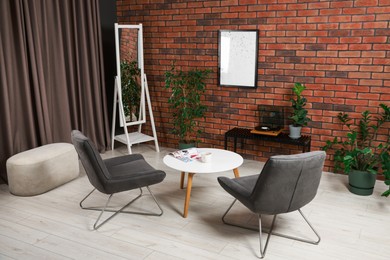 Photo of Soft armchairs, coffee table, mirror and houseplants in cozy living room. Interior design