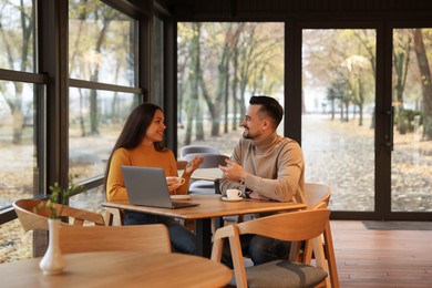 Photo of Colleagues with laptop working together at table in cafe