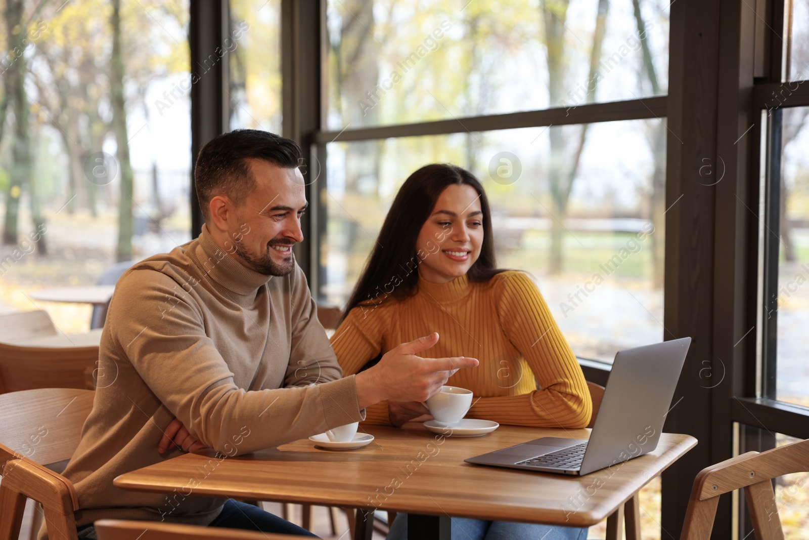 Photo of Colleagues with laptop working together at table in cafe