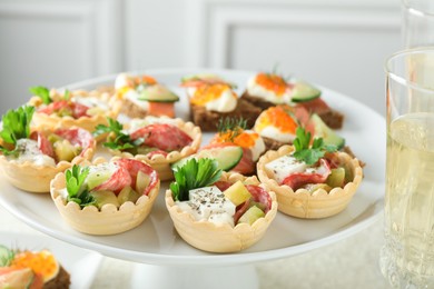 Photo of Many different tasty canapes and wine on white table, closeup