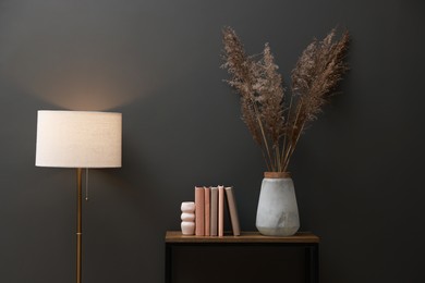 Photo of Console table with decor and lamp near grey wall in room. Interior design