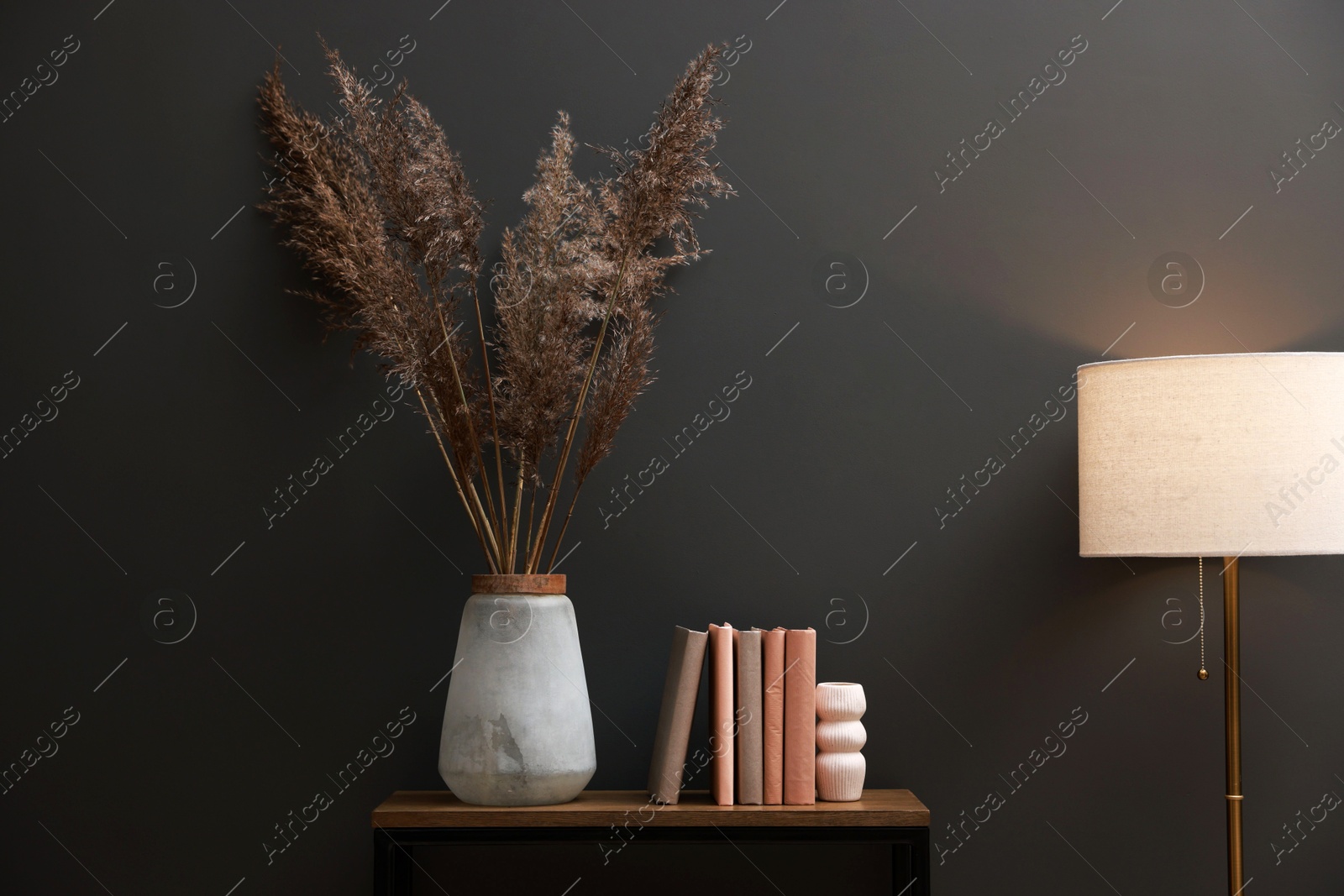 Photo of Console table with decor and lamp near grey wall in room. Interior design