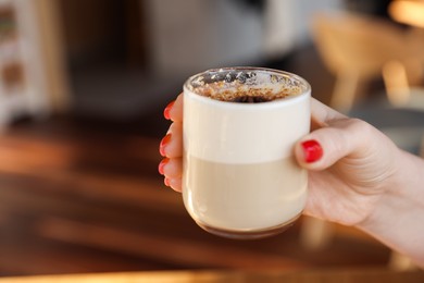 Photo of Woman with glass of aromatic coffee in cafe, closeup. Space for text