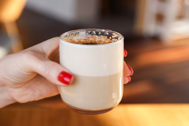 Photo of Woman with glass of aromatic coffee in cafe, closeup